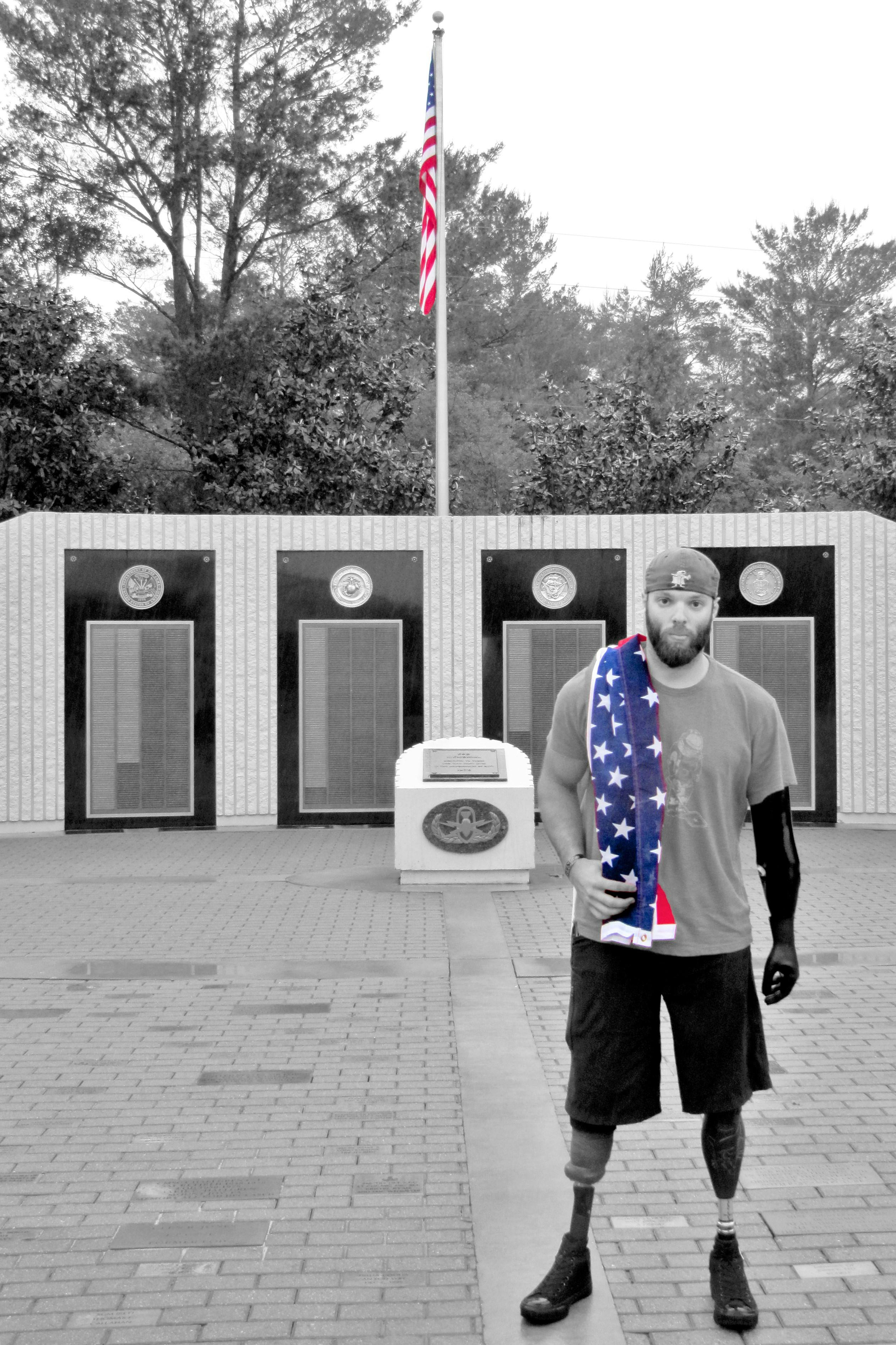 Andrew Bottrell holding the Stars & Stripes posing in front of a war memorial